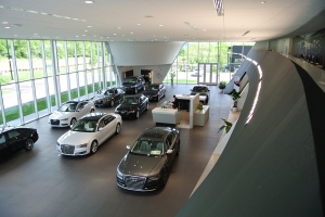 This elevated view of a car dealership's showroom illustrates how its lighting arrangement draws attention to their vehicles.